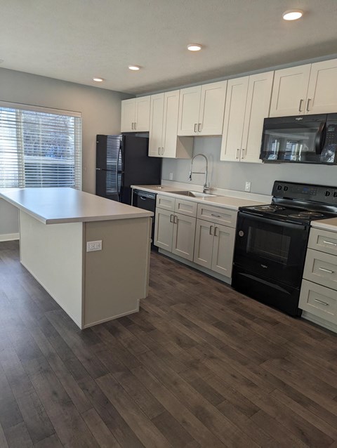 a kitchen with white cabinets and black appliances